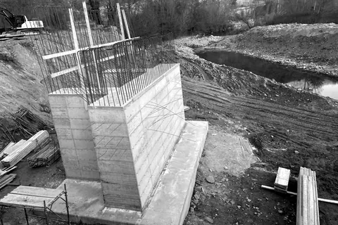 Muro in cemento armato gettato in opera, con ferri di ripresa, accanto a un corso d’acqua