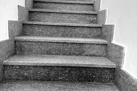 Scala interna finita con gradini in pietra e pareti tinteggiate di bianco